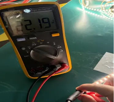 Digital multimeter showing 22.19V at the end of an anonymous 5m 24V LED strip